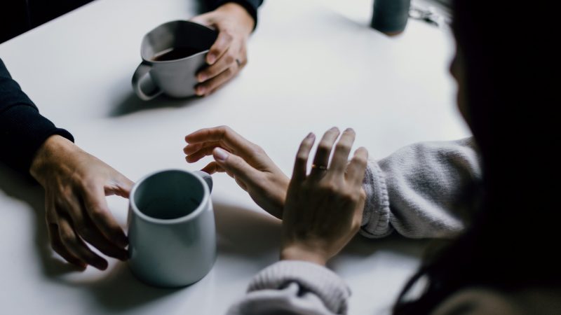 Anxiety Without Fear: The hands of two people talking over coffee, one passing the coffee mug to the other.